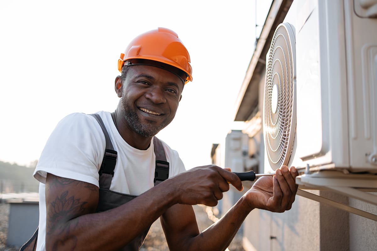 Craftsman repairing air conditioner with screwdriver on roof